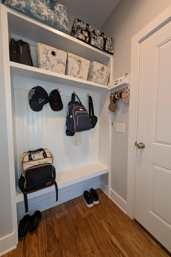 A built in bench with coat hooks and shelves for storage