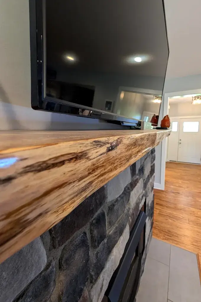 Close up view of a wooden mantel above a wood stove